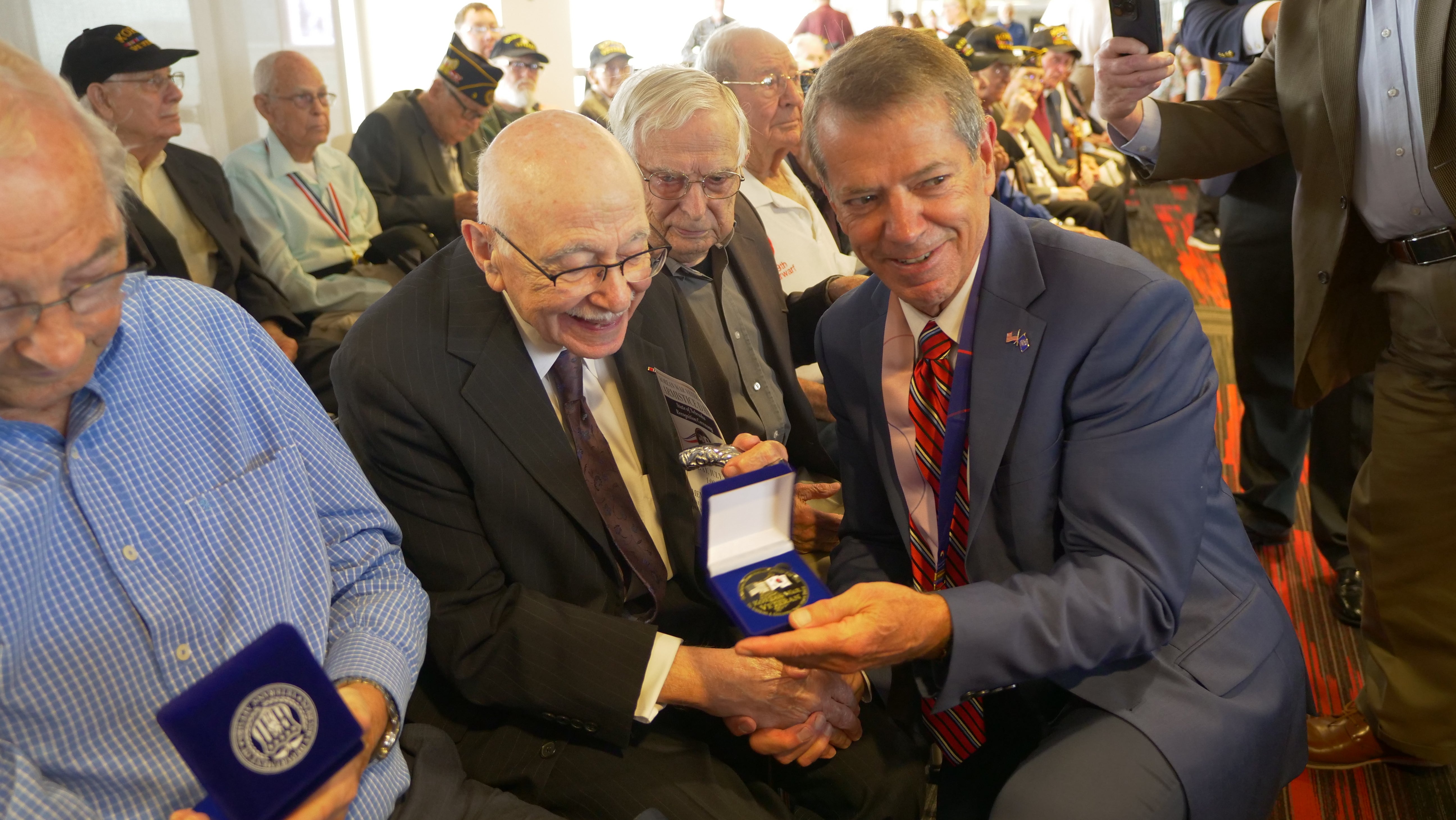 Gov. Pillen presenting State of Nebraska recognition coins to veterans in attendance of the ceremony.