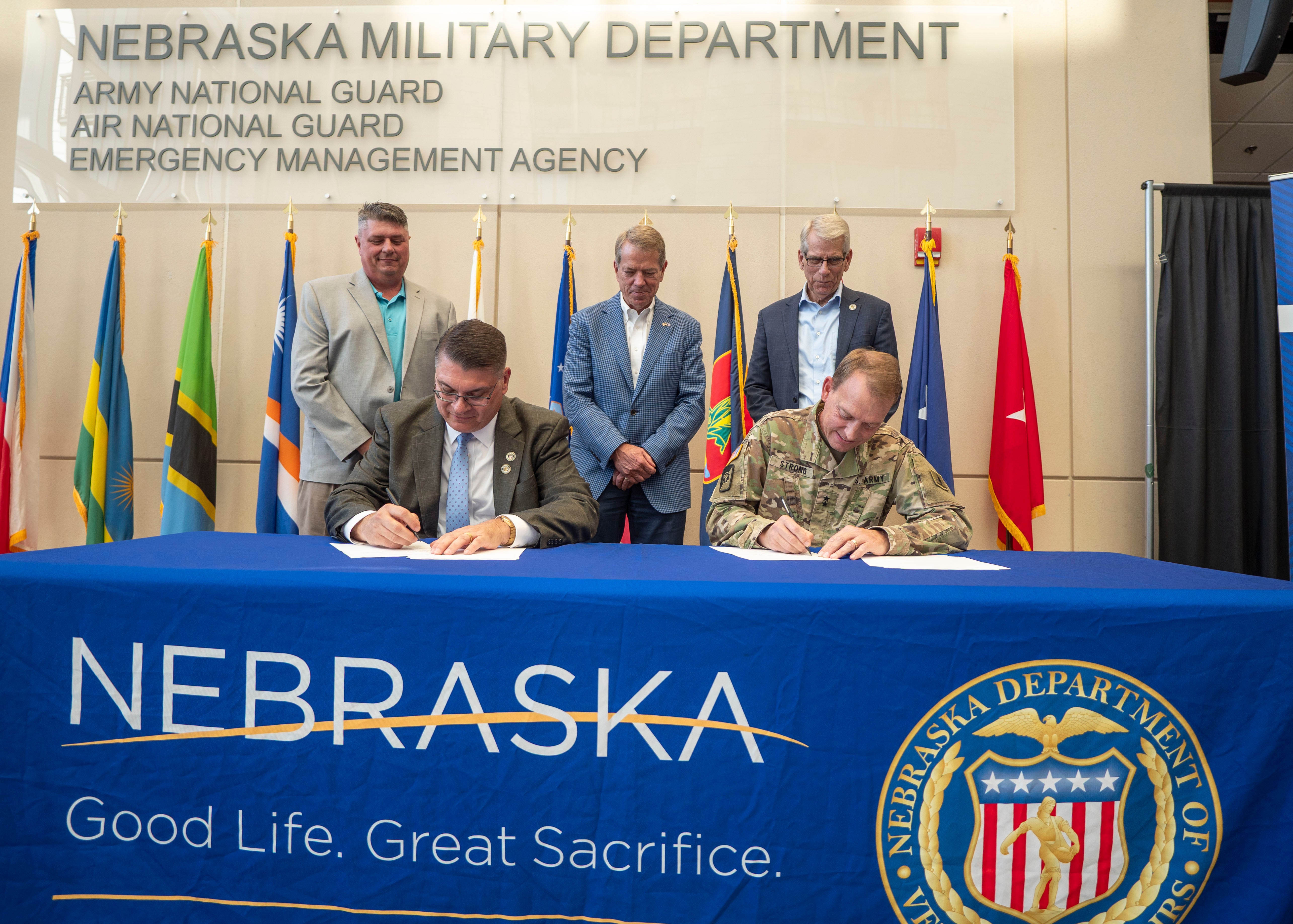 NDVA Director John Hilgert and Nebraska National Guard Adjutant General MG Craig Strong sign an MOU to establish a state veterans service office at Joint Force Headquarters in Lincoln as State Veterans Service Officer Dan Benes, Governor Jim Pillen, and Lieutenant Governor Joe Kelly watch. 
