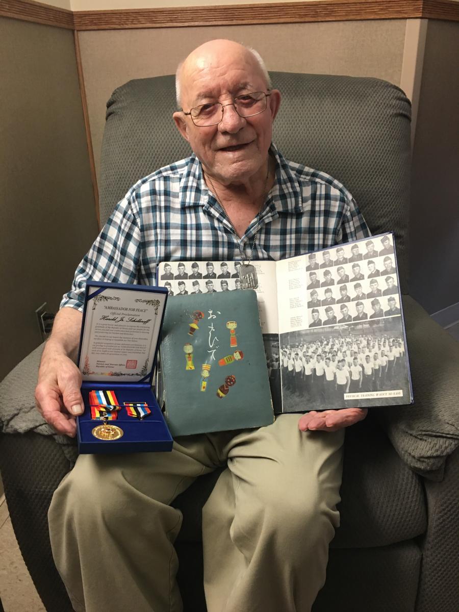 Harold Schillereff holding Ambassador for Peace medal and photographs