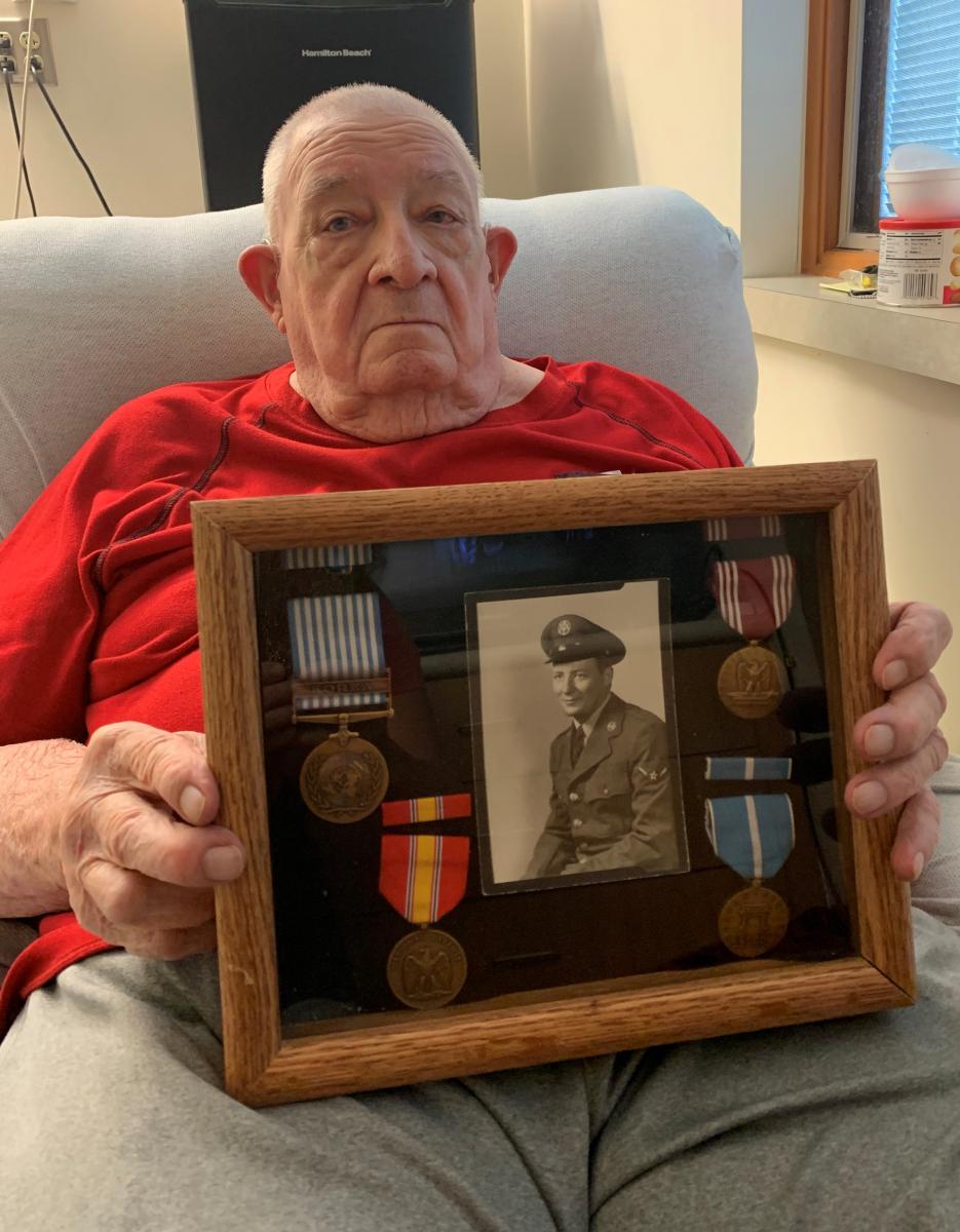 Marvin Danielson holding case with photo and medals