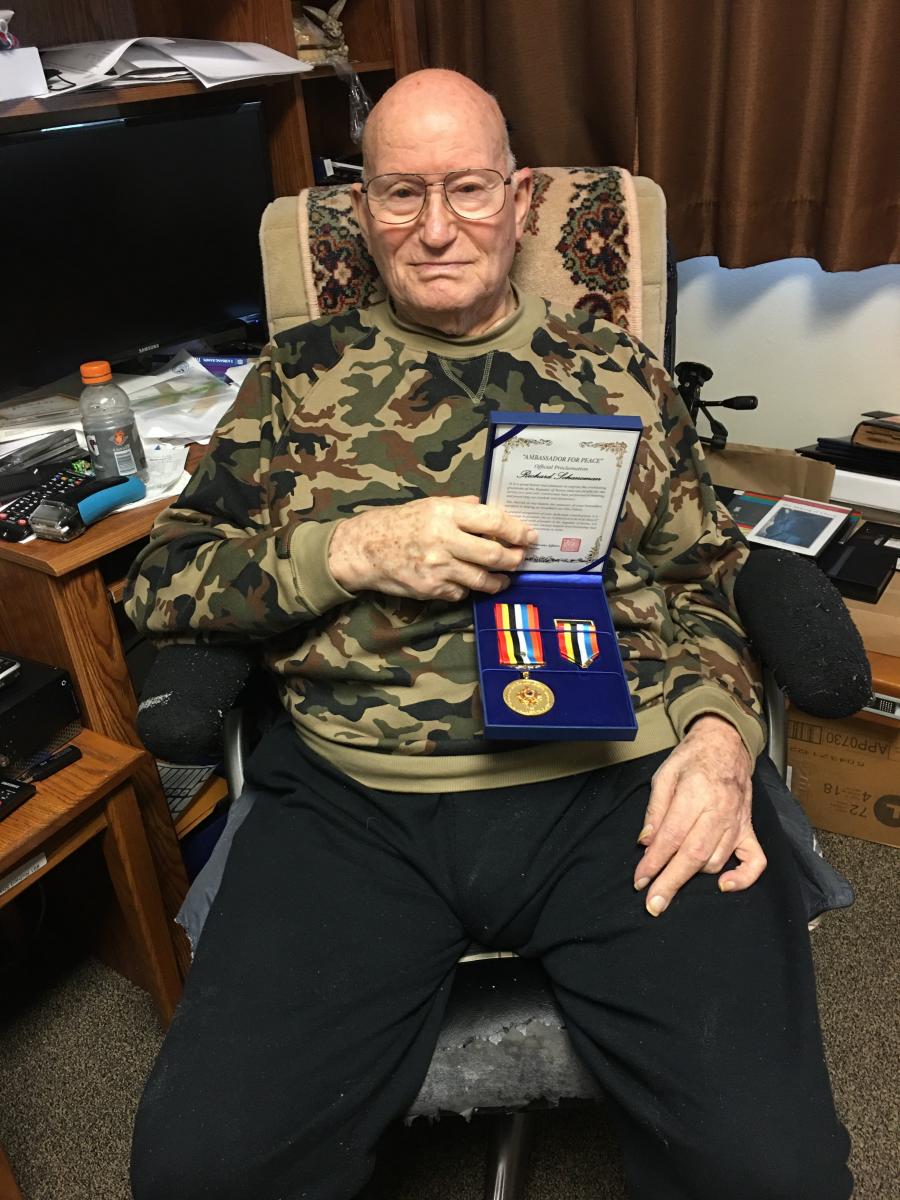 Richard Schaneman holding Ambassador for Peace medal