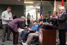 Gov. Pillen presents a recognition medal to World War II veteran Don Graper at the Central Nebraska Veterans’ Home. Seated next to him are fellow veterans Dr. John Finkner (left) and Doug Graul (right). Also pictured are NDVA Director John Hilgert (far left), Senator-elect Stan Clouse (right), and Senator John Lowe (far right).