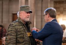 Governor Jim Pillen pins a lapel pin on a Vietnam War Era Veteran.