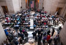 A crowd of attendees watches NE National Guard Adjutant General Craig Strong give remarks