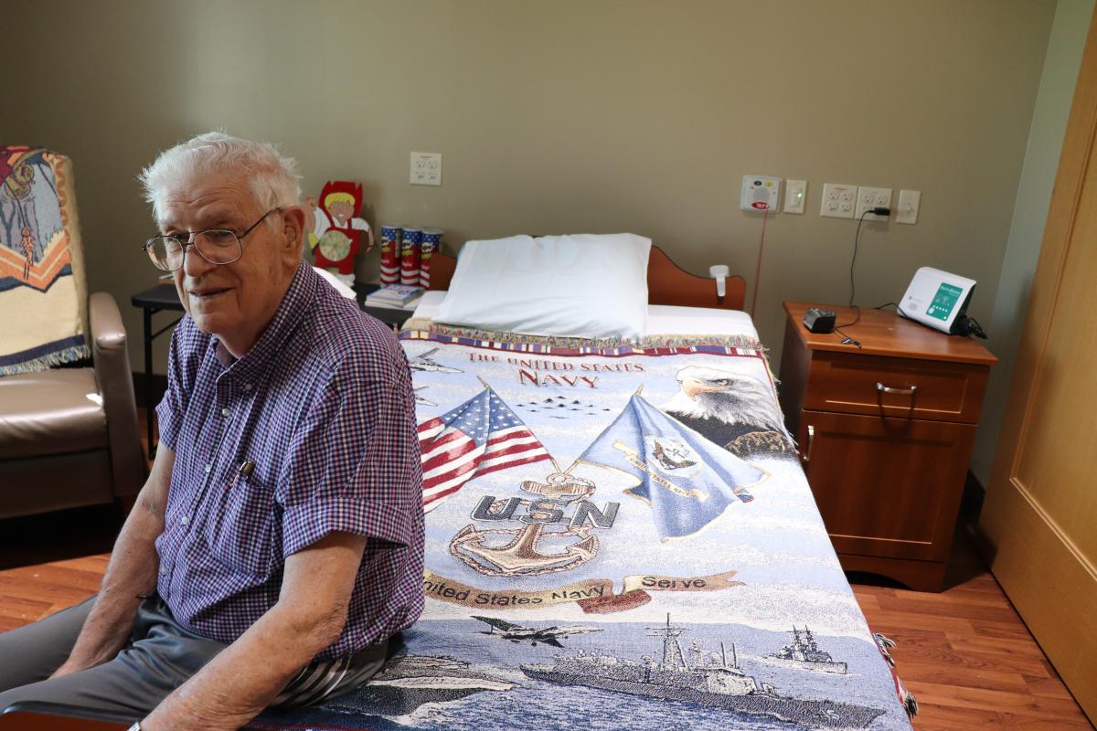 Kyle Lantz sitting on bed with US Navy blanket