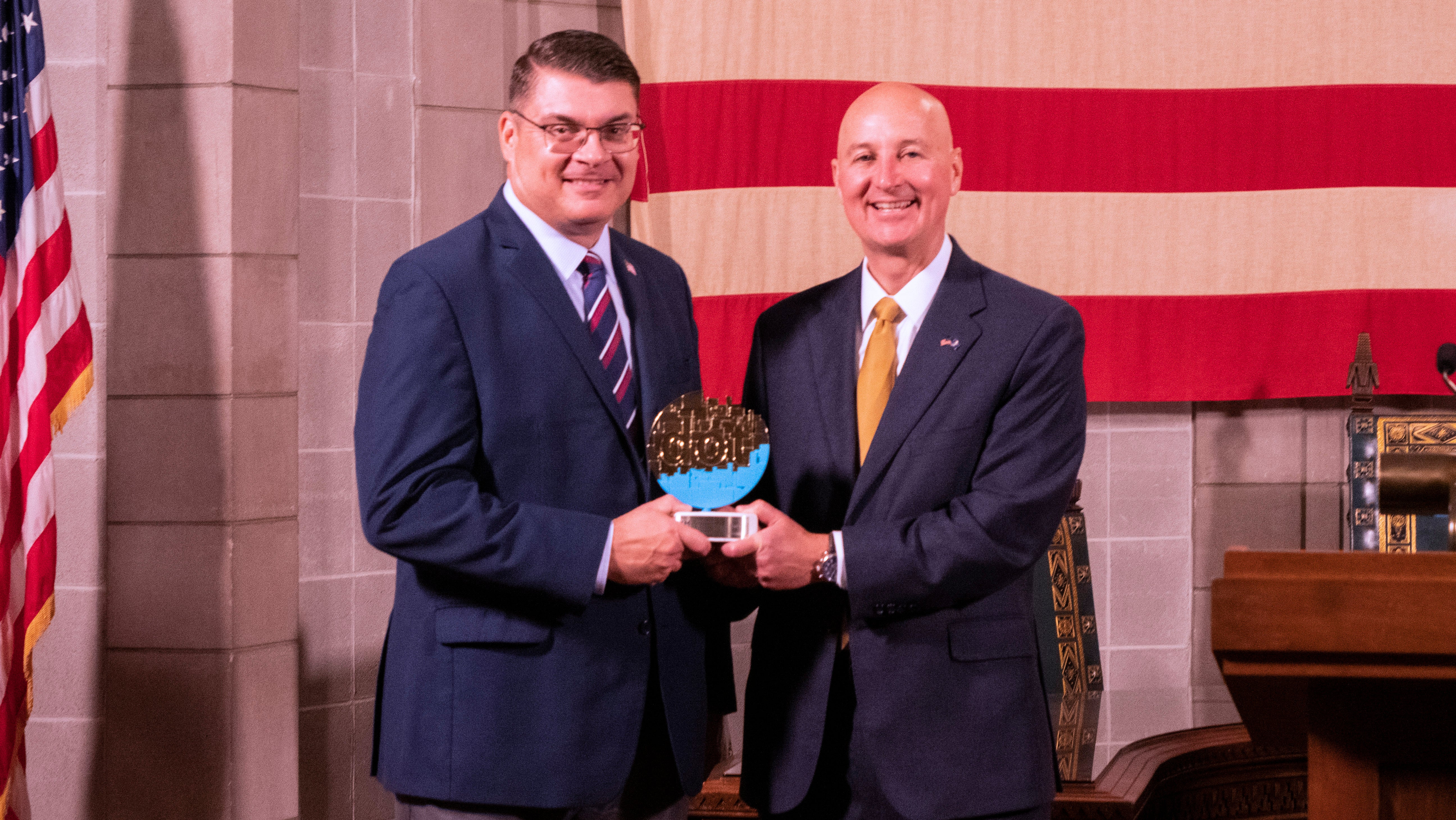 Governor Ricketts (right) and NDVA Director John Hilgert (left) with the dotCOMM Gold Award. 